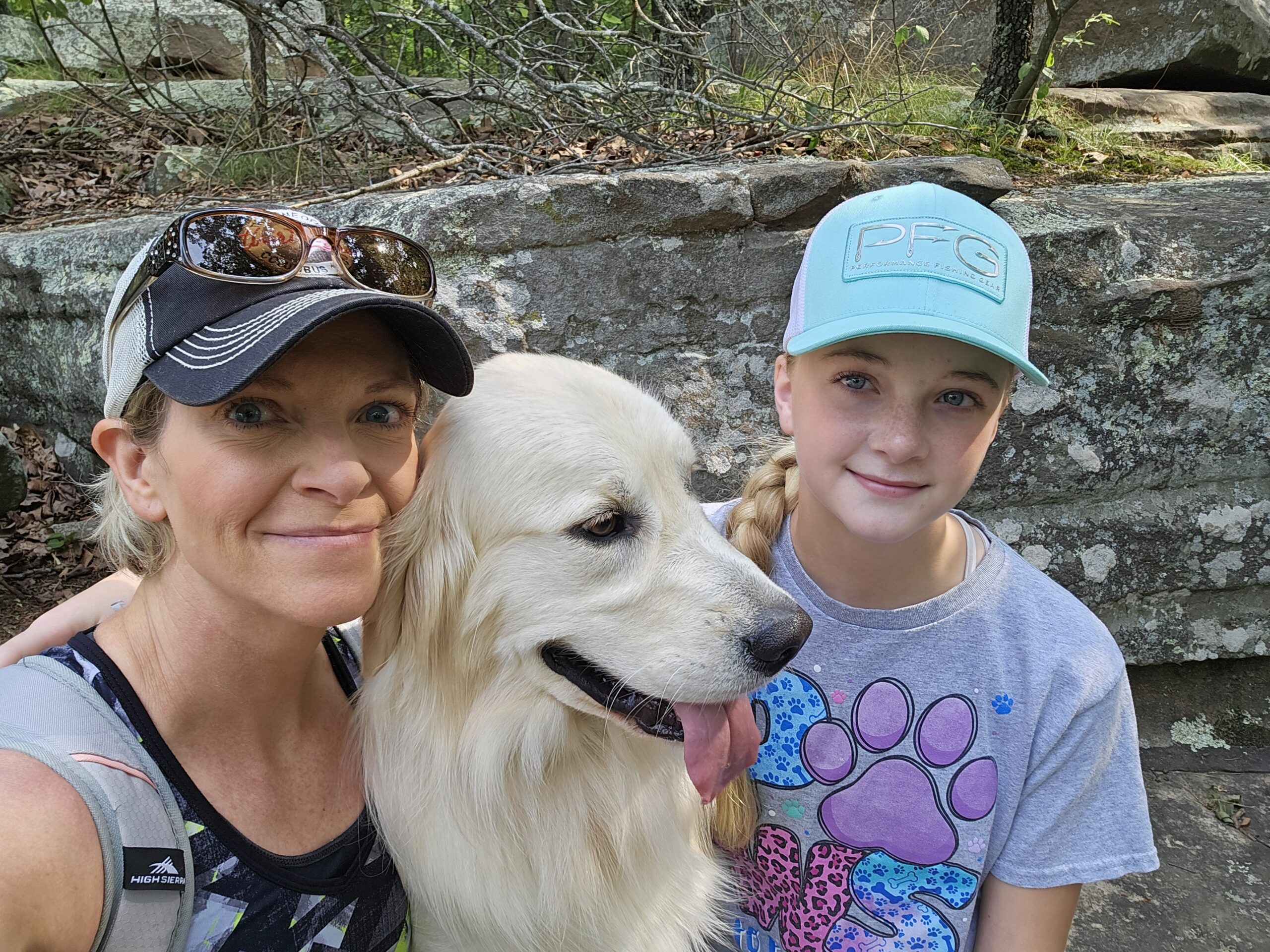 a dog sitting between two smiling people in the outdoors, The Benefits of Being Active with Your Pet: Why Bonding Matters